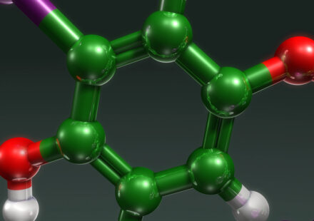 3D molecular model of a benzene ring with green carbon, red oxygen, white hydrogen, and purple atoms